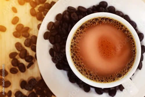 Hot coffee in white cup with roasted coffee beans on wooden table background, Top view. For Interior coffee shop.