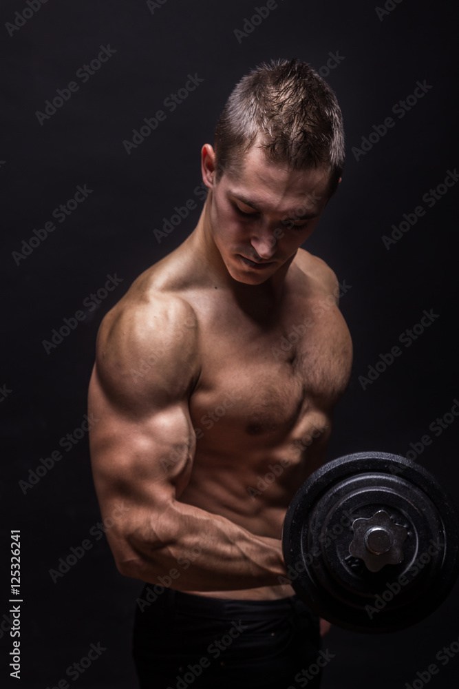 young man bodybuilder looking down, dumbbells exercise.