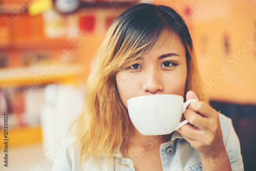 Young beautiful woman drinking hot cappuccino coffee at cafe.