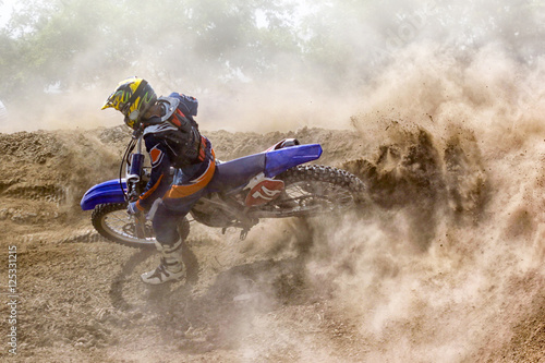 Motocross rider creates a large cloud of dust and debris