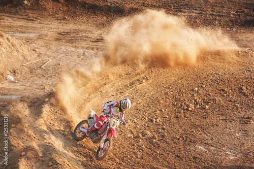 Motocross rider creates a large cloud of dust and debris