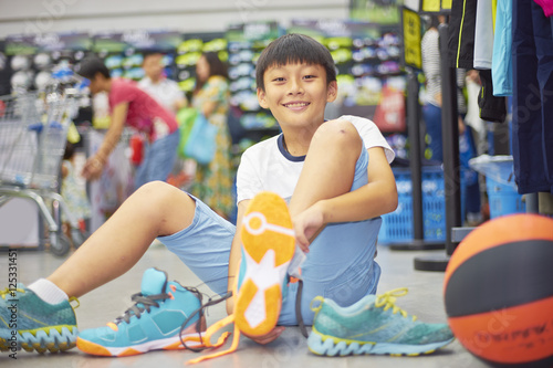 Photography boy smilding trying sports shoes in shopping mall