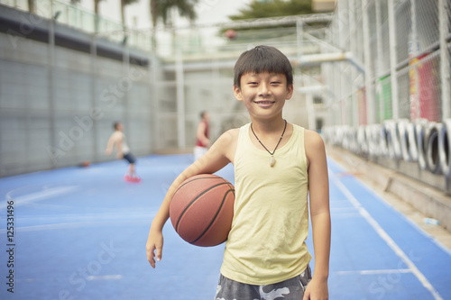 boy standing smiling at camera with basketball