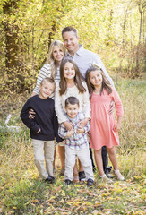 Beautiful Young Family Portrait with fall colors in the background outdoors