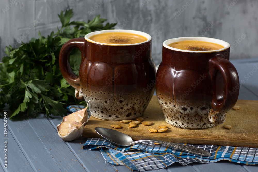 pumpkin cream soup in mugs on gray blue background pumpkin cream soup in mugs on gray blue background