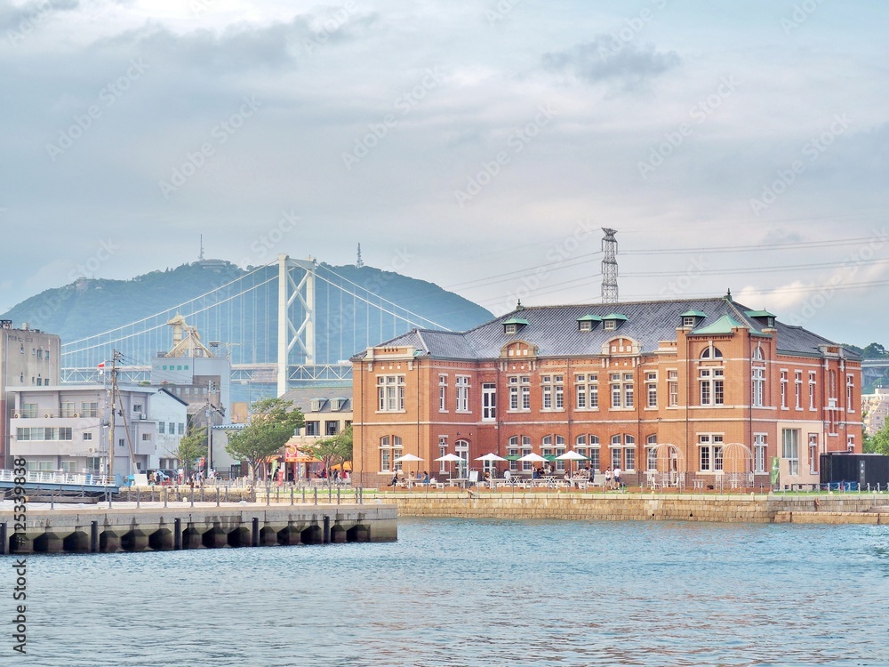 Fototapeta premium Old Moji Customs Office, built in 1912 at Moji port in Kitakyushu, Fukuoka , Japan. In the building has a coffee shop and art gallery. Kanmonkyo Bridge on background.