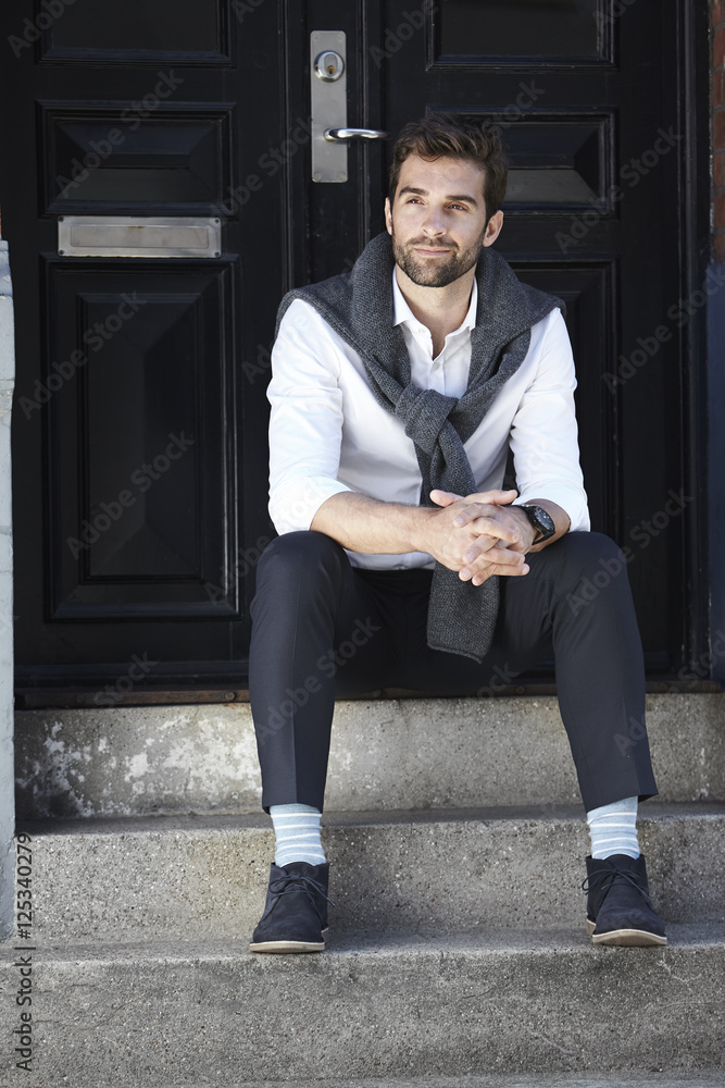 Handsome man sitting on steps, looking away Handsome man sitting on steps, looking away