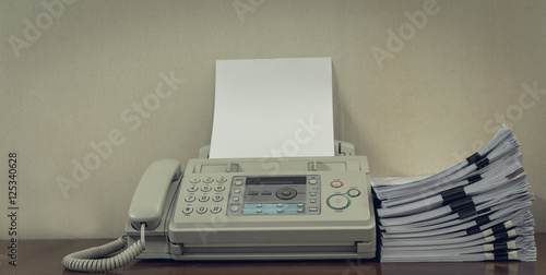 old fax machine on the table and stack of paper. photo