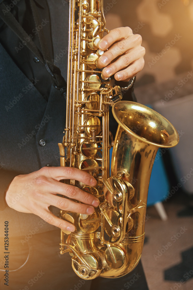 Obraz premium Young man in a suit hold a saxophone musical instrument