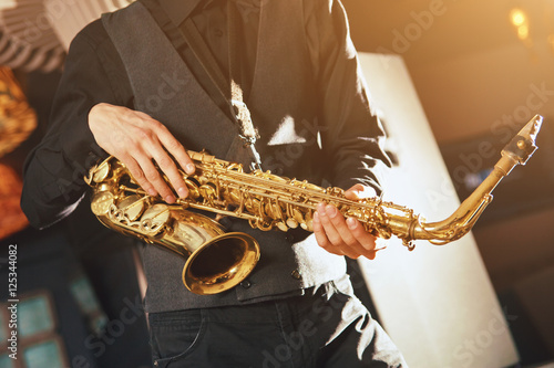 Young man in a suit hold a saxophone musical instrument