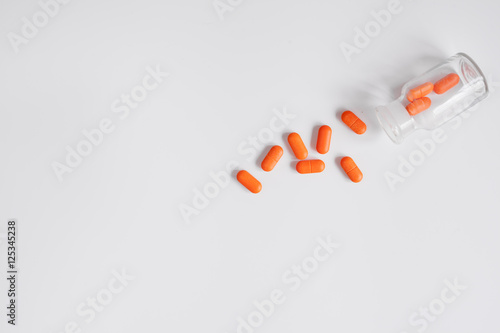 orange pills in glass bottle on white background