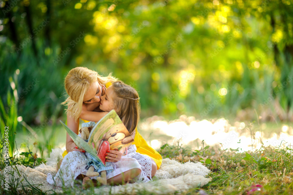 mother reads the book in the daughter on a grass mother reads the book in the daughter on a grass