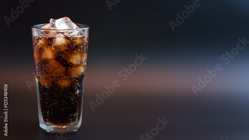 Cola with ice in glass on black background 