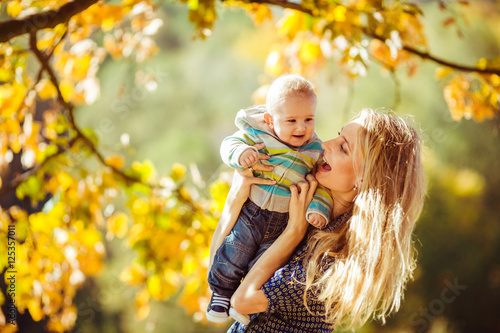 Beautiful and happy mother with her little boy playing outdoors