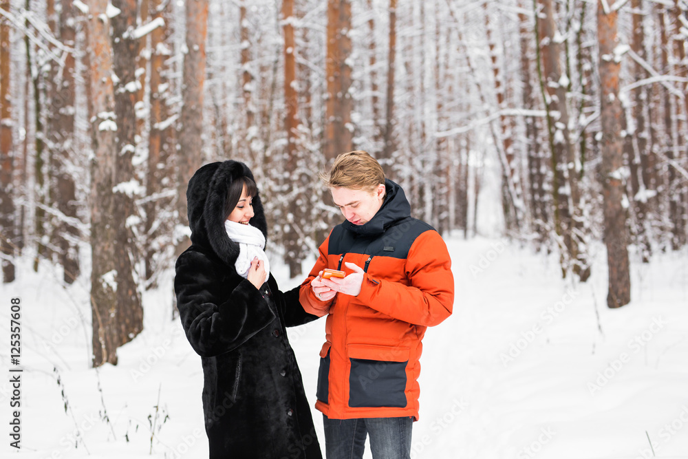Happy couple consulting a smart phone in winter outdoors