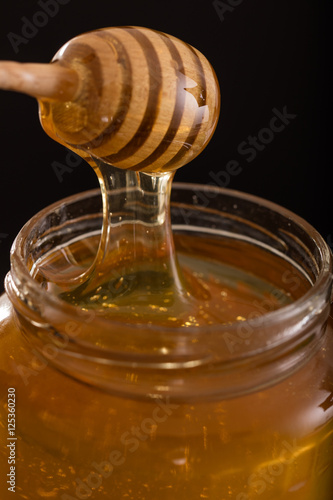 Close-up of a jar of honey with wooden dipper 1