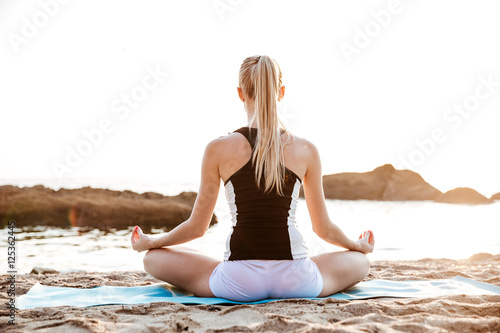 Back view of a young woman sitting in lotus position