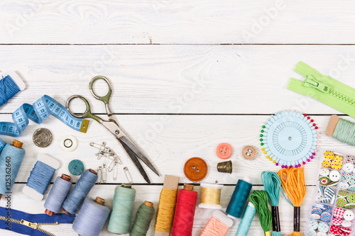 Tools and accessories for sewing on light wooden background.