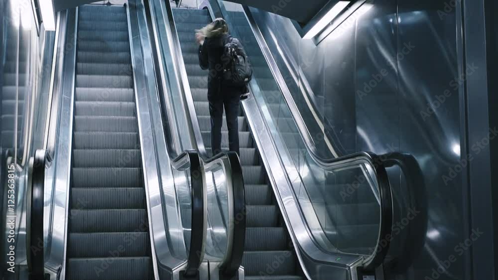 Young woman with bag moving on escalator. Modern escalator stairs moving up. Young woman with bag moving on escalator. Modern escalator stairs moving up.
