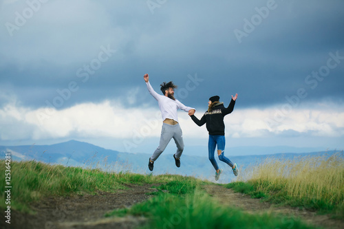 Couple bouncing on gray sky