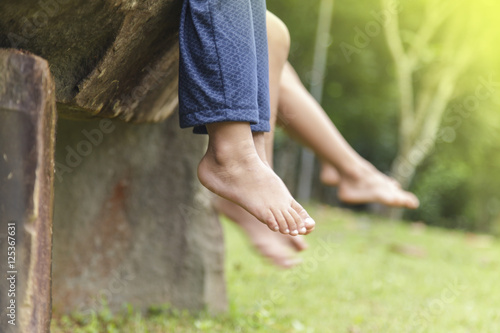 Billede på lærred Children legs barefoot, Kids sitting dangling their feet in summ