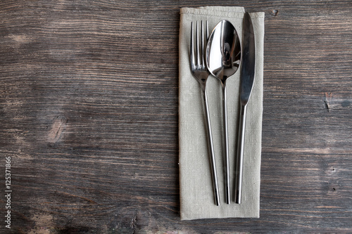Concept of simple organic food - laconic design cutlery set on rustic wooden table and linen tissue. Top view.