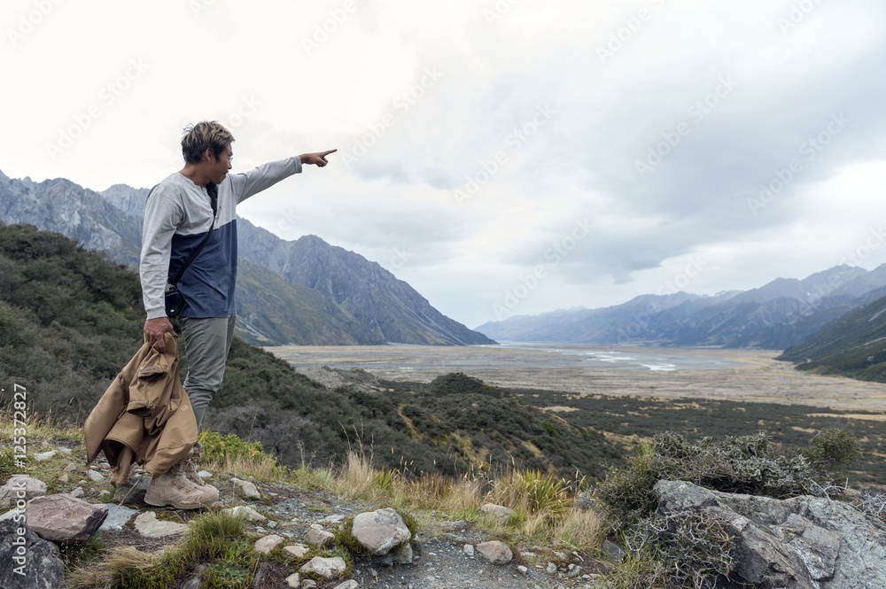 A man looking at the Tasman River from viewpoint along the walking trail to the Blue Lakes and Tasman Glacier View in Aoraki / Mount Cook National Park