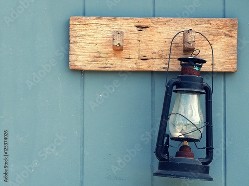 Burning kerosene lamp hang on the wooden wall. Home decoration by old lamp in vinage style. photo