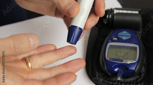 Measuring glucose level blood test using ultra mini glucometer and small drop of blood from finger and test strips. Dependent first type diabetes patient.