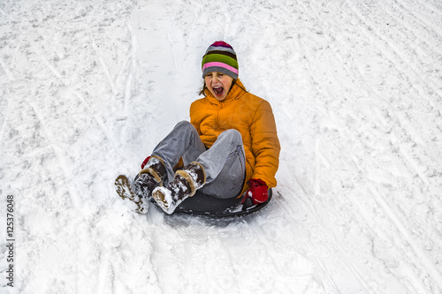 girl has fun sledging down the snowy hill