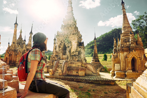 Traveller with backpack resting and looks at Buddhist stupas. © soft_light