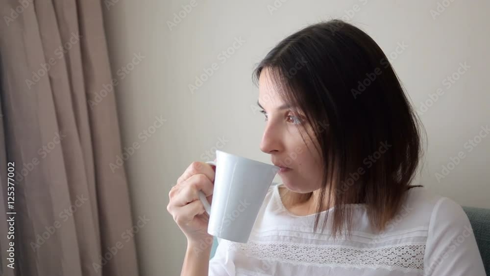 young girl sitting on chair and drinking tea from a mug in the room young girl sitting on chair and drinking tea from a mug in the room