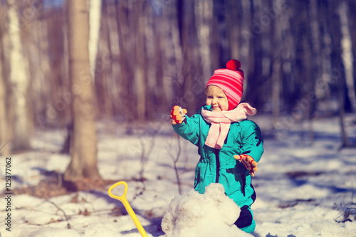 little girl digging snow in winter, kids activities