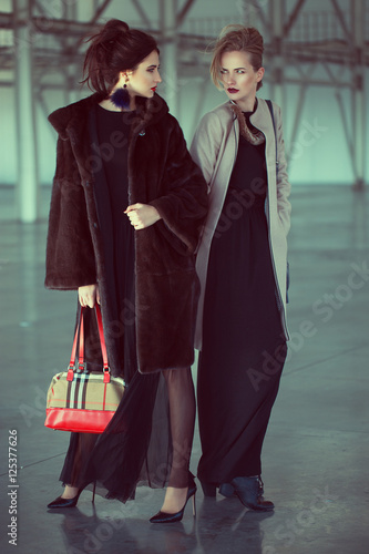 Two models at airport are waiting private airplane. fashion look, stylish make up, perfect hairdo and interesting individual bags