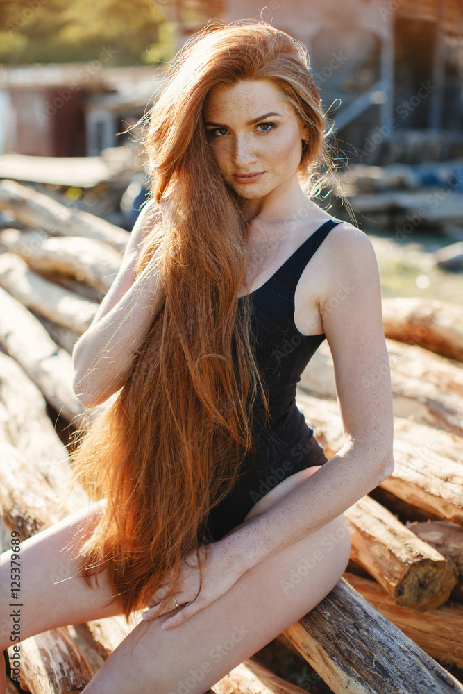 Portrait of sexy redheaded woman,long thick hair,the freckles on the face  and body,dressed in black closed swimsuit,slender beautiful figure posing  outdoors in the summer in the countryside foto de Stock | Adobe