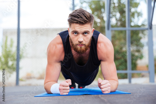 Sportsman doing plank exercise on blue fitness mat during workout