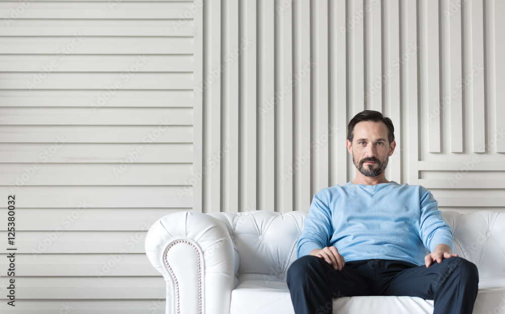 Handsome confident man sitting in the middle of the couch Handsome confident man sitting in the middle of the couch