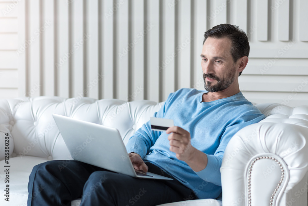 Pleasant attractive man entering data of his credit card Pleasant attractive man entering data of his credit card