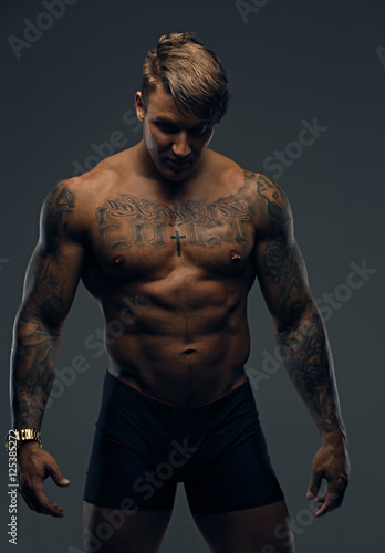 Portrait of tattooed muscular male in a shadow.