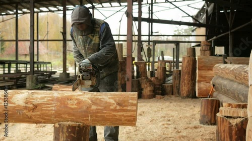 Wallpaper Mural Man cuts wood chainsaw for future home. Protective face mask on the face of the builder and a lot of sawdust. Hangar with a part of the future home on the background Torontodigital.ca
