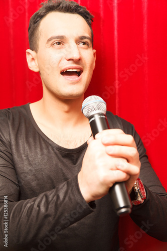 young man singing with a microphone on a red background