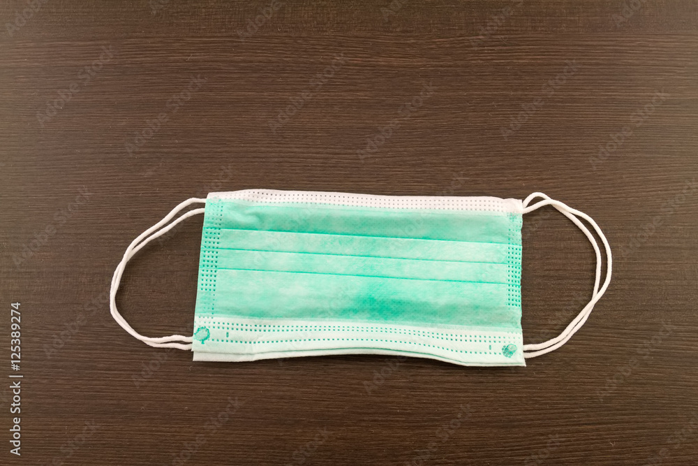 Disposable surgical ear-loop mask stack on black wooden background Disposable surgical ear-loop mask stack on black wooden background