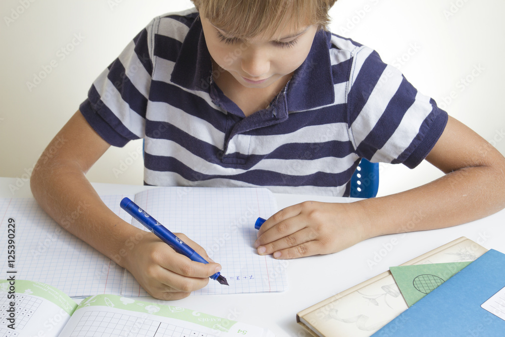 Little kid writing on notebook while doing homework at home. Close up Little kid writing on notebook while doing homework at home. Close up