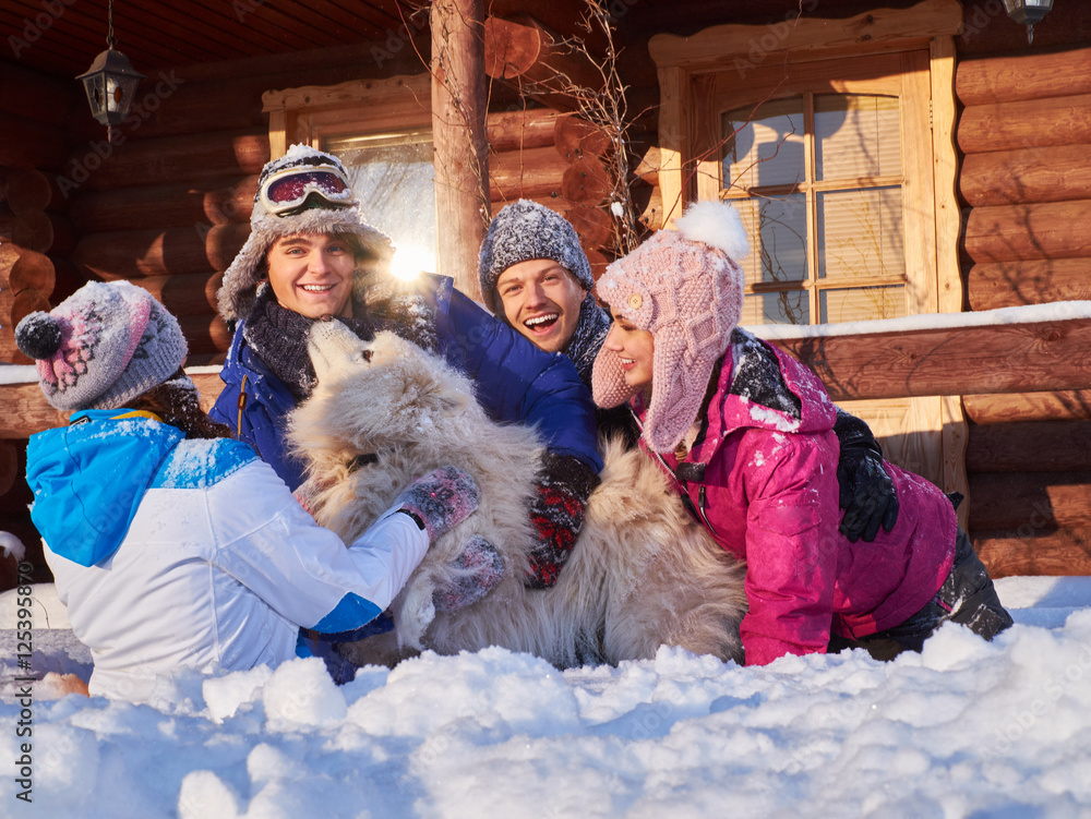 Cheerful friends with dog spend winter holidays together at mountain cottage