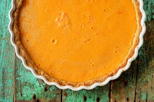 Fresh round bright orange homemade pumpkin pie in white baking d