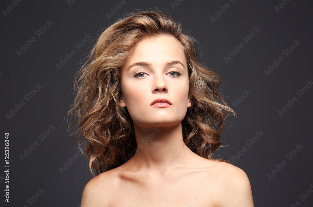 Obraz premium Portrait of beautiful young woman with long hair on grey background
