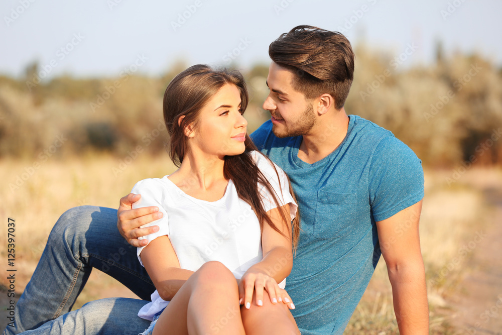 Beautiful young couple sitting together in a meadow Beautiful young couple sitting together in a meadow