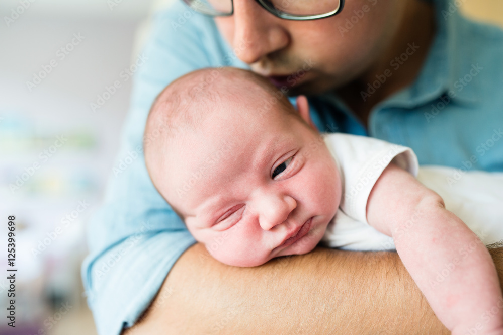 Close up, unrecognizable father holding his newborn baby son Close up, unrecognizable father holding his newborn baby son