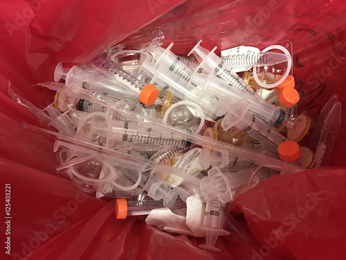 In an HIV testing laboratory, single-use plastic syringes, pipettes, and filters are disposed of in a red hazardous materials waste bag.