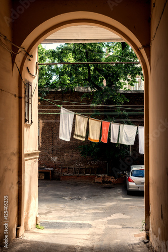 Arch in the old town. Wash linen drying on a rope over the doorway. © vladk213